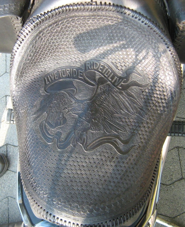a motorcycle seat with fine detailed leatherwork showing an eagle and live to ride 